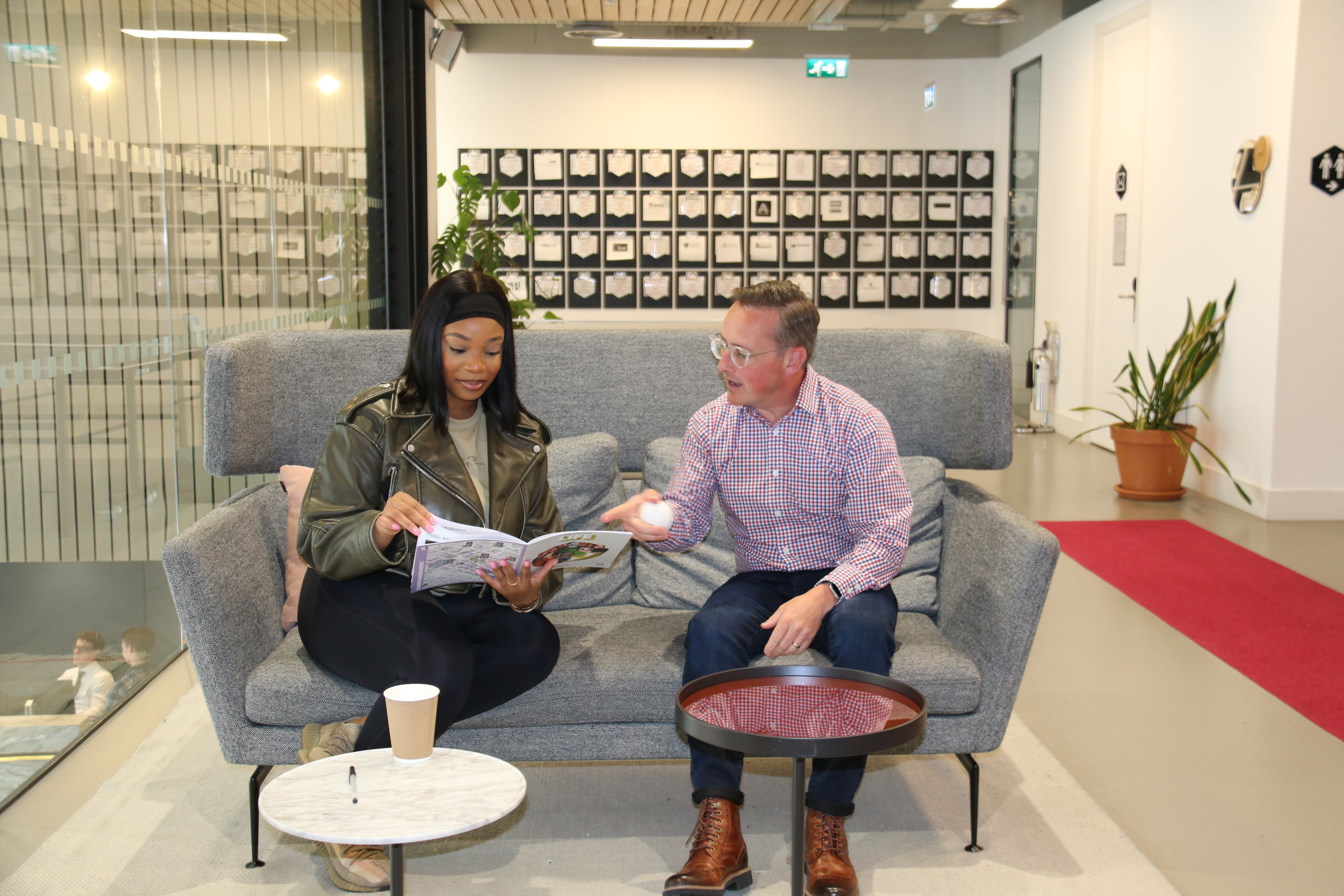 Image of two people sat on a sofa looking through a textbook.